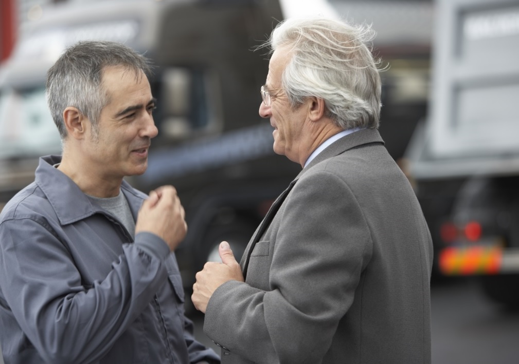 Camionneur et patron discutent dans une cour d’entreprise de camionnage.