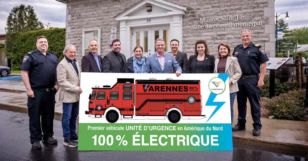Groupe autour d’une affiche illustrant le camion électrique d’incendie de Varennes.
