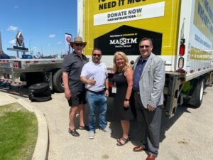 Des employés de Maxim Truck & Trailer ou de Harvest Manitoba devant une remorque.