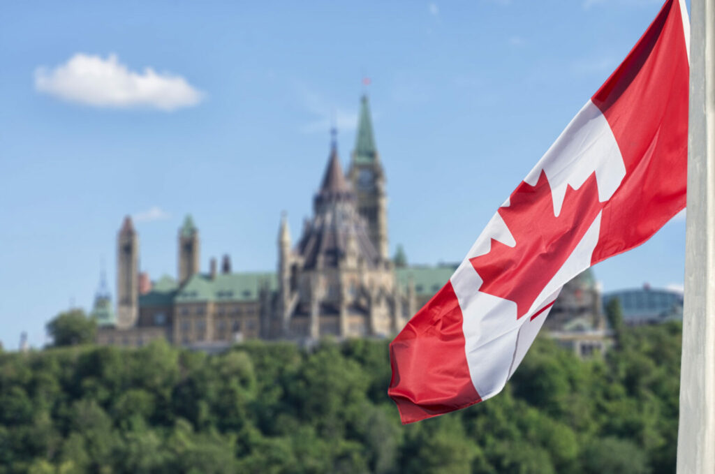 Drapeau du Canada avec parlement en arrière-plan.
