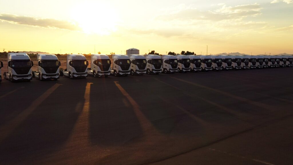 Rangée de camions Nikola Tre à batteries au soleil couchant.
