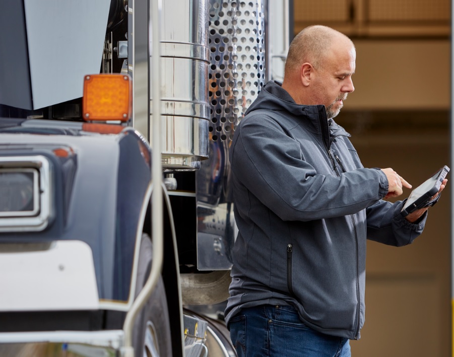 Chauffeur à côté de son camion qui utilise une tablette Isaac.
