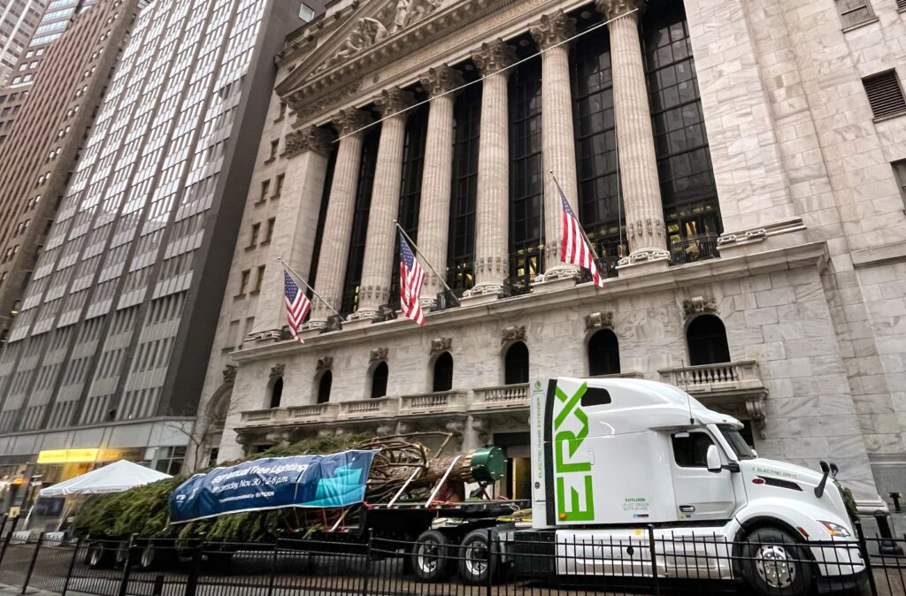 Camion Hyliion de côté devant la Bourse de New York avec un arbre de Noël sur flatbed.