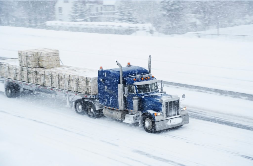 Camion vu de haut sur l’autoroute dans une tempête de neige.