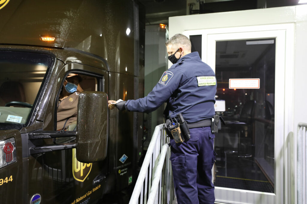 Agent frontalier canadien échange des documents avec un camionneur UPS