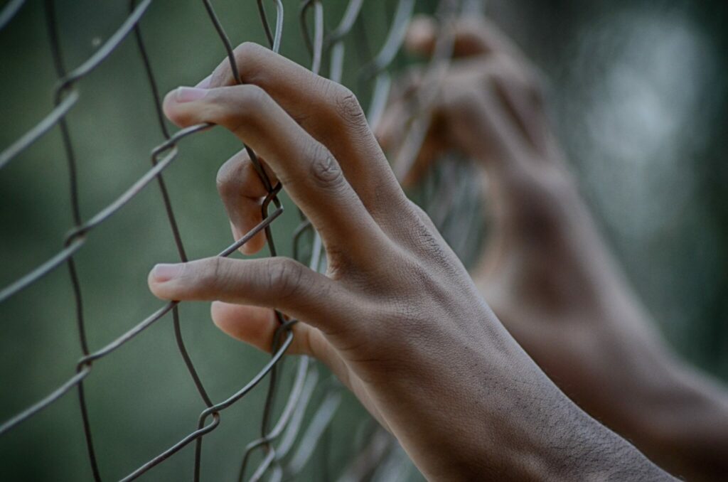 Mains qui s’accrochent à une clôture de prison