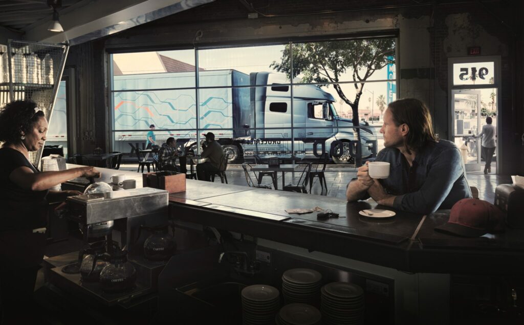 Camionneur prend un café dans un petit resto, camion stationné dans la rue.