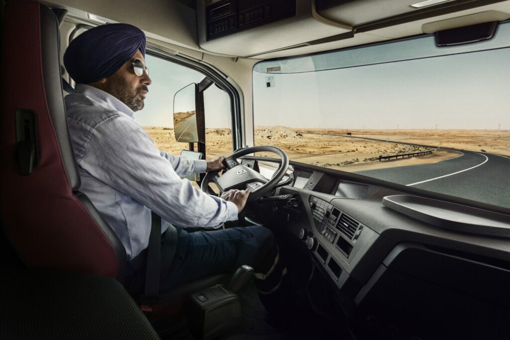 Chauffeur avec turban et lunettes fumées au volant d’un camion Volvo