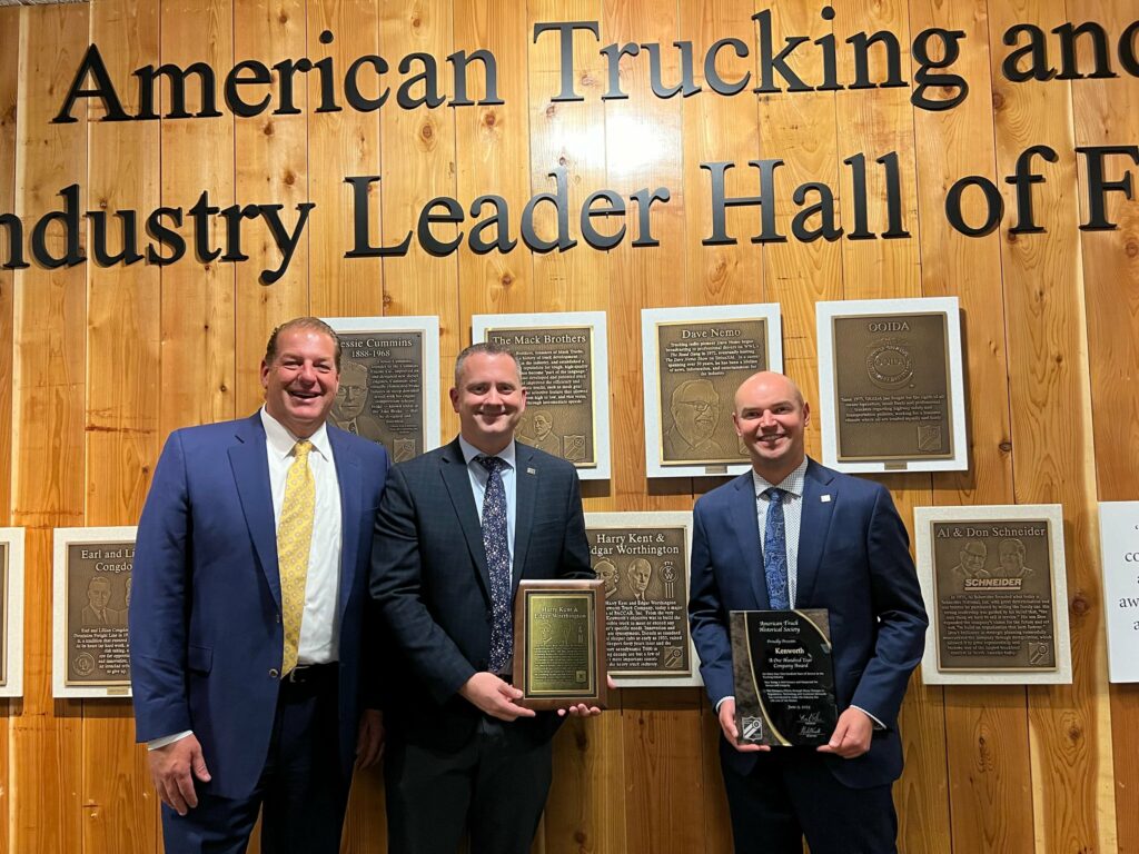 Trois personnes avec des plaques pour l’intronisation des fondateurs de Kenworth au temple de la renommée Trucking and Industry Leader Hall of Fame.