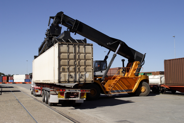 Machinerie lourde place un conteneur sur un camion.