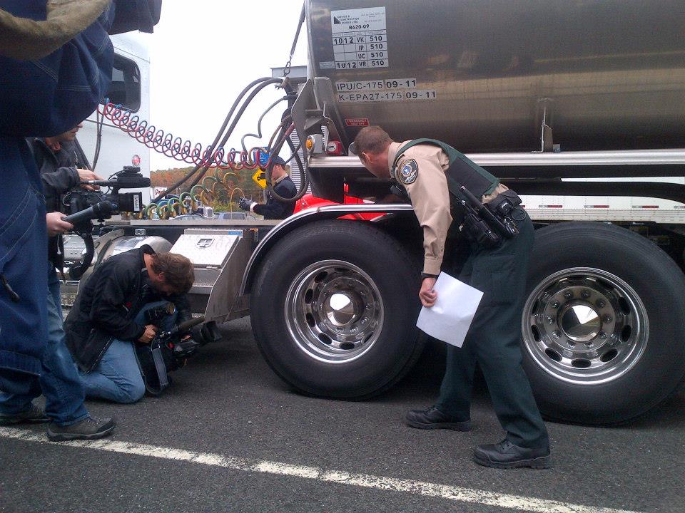 Médias et public assistent à une démonstration d’un contrôleur routier près d’un camion.