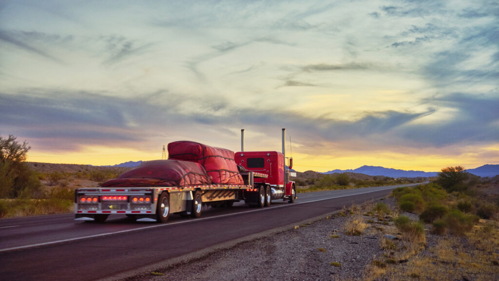 Camion et remorque flatbed vus de dos sur autoroute désertique