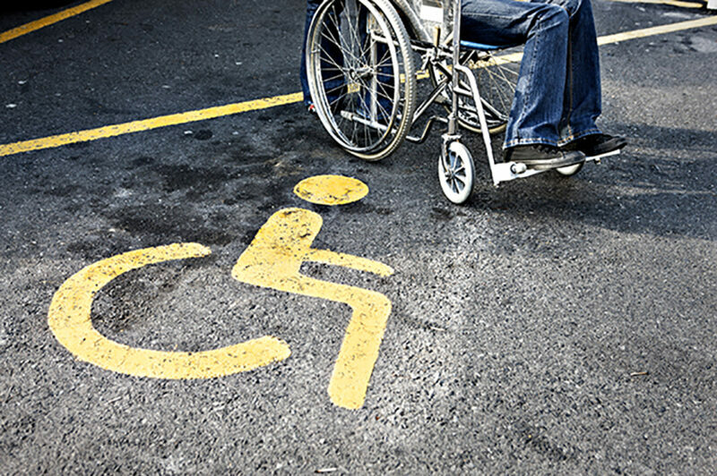 Personne en fauteuil roulant dans place de stationnement pour handicapés